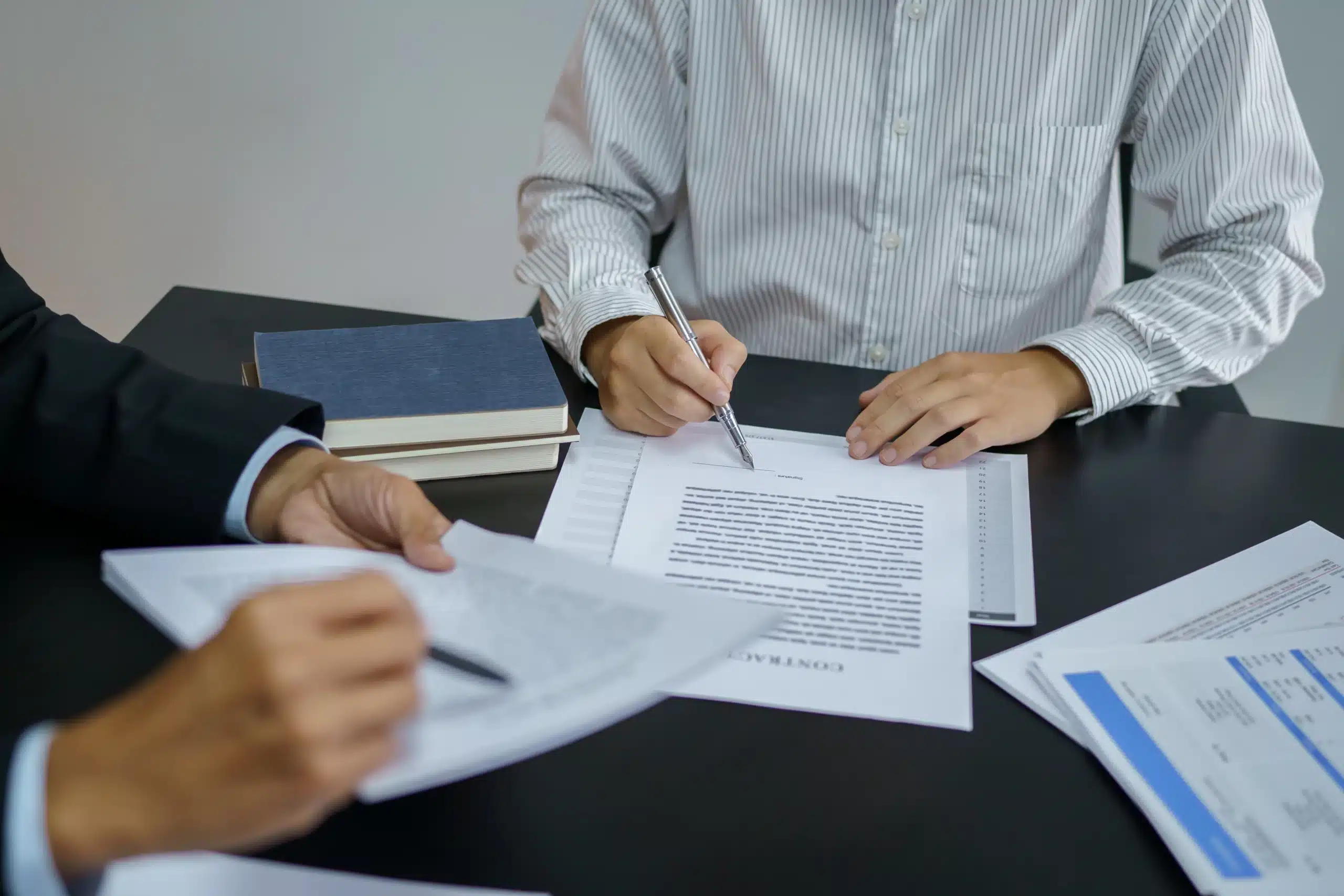 Texas landowner and attorney reviewing and signing an eminent domain agreement at a table.